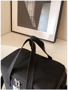 Close-up of black oxford cloth diaper bag featuring minimalist FA label and metal zippers