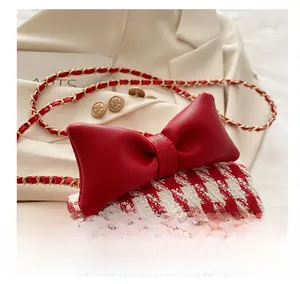 Detail of red houndstooth tweed girl's purse with leather bow and gold chain strap