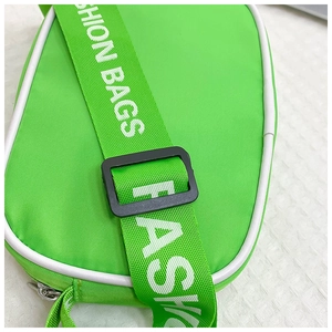 Detail of neon green nylon kids crossbody bag with white piping and FASHION BAGS strap