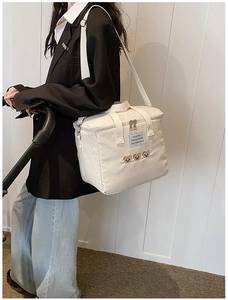 Side view of cream canvas diaper bag with cute bear embroidery and wide handles