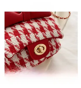 Detailed view of red houndstooth fabric bag with large leather bow and golden twist lock