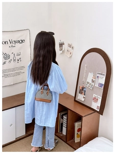 Girl wearing a mini houndstooth shell bag with brown leather trim in a cozy room