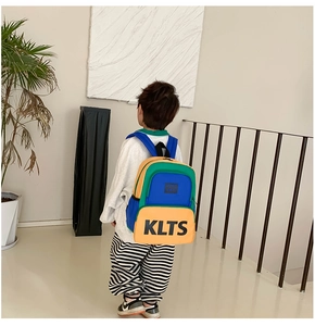 Detail of color-block kids backpack with yellow, green and blue panels and bold lettering