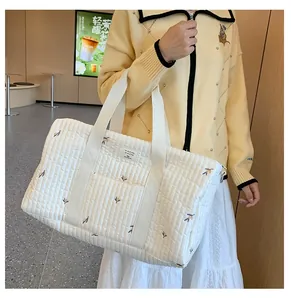 Detailed close-up of quilted white canvas diaper bag with delicate floral embroidery
