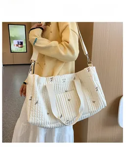 Close-up of quilted white tote bag with leaf embroidery and dual strap detail