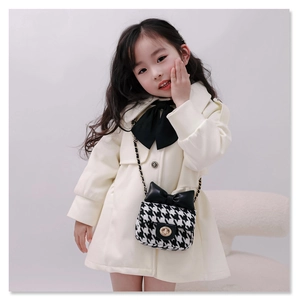 Detail showing a mini black and white houndstooth chain bag with a decorative bow