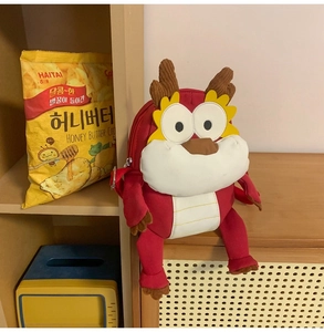 Vue détaillée du sac à dos dragon en peluche rouge avec fermeture éclair et sangles