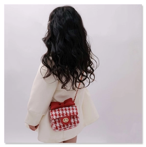 Detail view of red houndstooth tweed girl crossbody bag with bow and gold chain strap