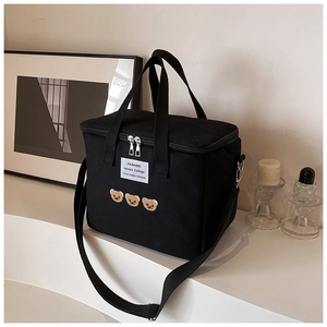 Detail of embroidered bears and brand label on a premium black canvas diaper bag