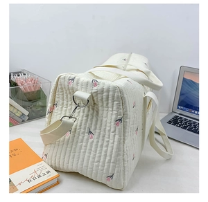 Close-up of quilted cream baby travel bag with pink tulips and detachable strap