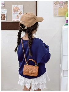 Détail d'un sac bandoulière marron matelassé pour fille avec fermoir à silhouette décorative