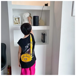 Detail of yellow nylon kids crossbody bag with purple lettering worn by a child
