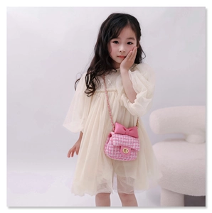 Girl's pink plaid crossbody bag with bow detail and gold chain strap on chair