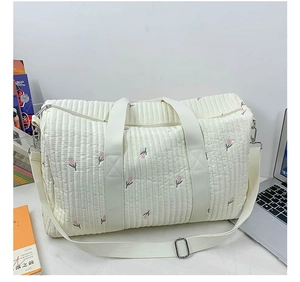 Detailed quilted travel bag featuring pink tulip embroidery and adjustable shoulder strap
