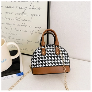 Detailed close-up of a child's houndstooth shell bag with brown leather handles and chain