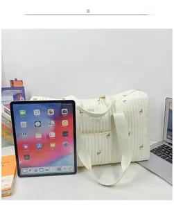 Quilted white tote bag with pink tulip patterns holding a laptop and books for school