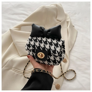 Close-up of houndstooth wool fabric texture and golden metal twist lock on the girl's bag