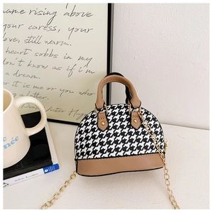 Detail of kids shell bag featuring houndstooth pattern and brown leather handle