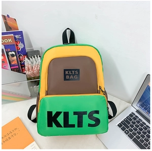Close-up of contrast color patchwork schoolbag with large bold letter prints on desk