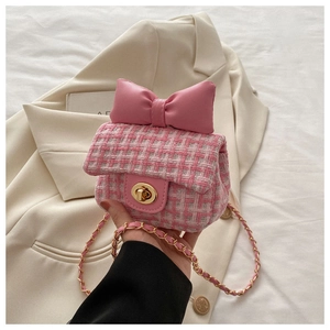 Detail of pink tweed crossbody bag with a leather bow and golden chain strap for girls