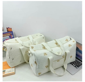Detailed view of quilted diaper bags with cute bear print and olive leaf embroidery