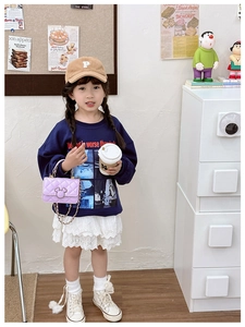 Détail d'un mini sac à chaîne matelassé violet clair porté avec sweat et jupe en dentelle