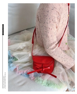 Detail of red patent leather kids crossbody bag with decorative bow and shoulder strap