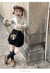 Detail of a brown leather mini round bag with a bronze chain strap on a child's outfit