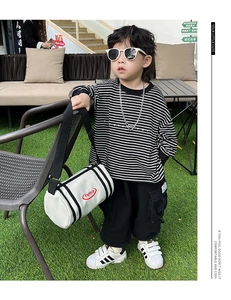 Detail of white canvas bucket bag with red logo on child casual striped outfit