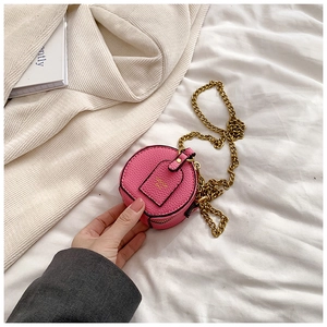Detailed macro view of pink round mini bag featuring pebble leather and gold chain strap
