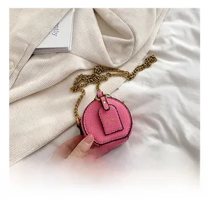 Detail showing pink round mini bag with gold chain strap and pebbled leather texture