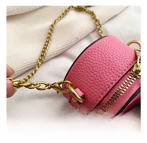 Detail view of pink textured leather mini round bag with gold chain strap and metal hook