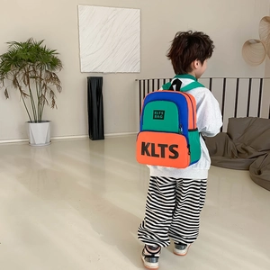 Kids color-block backpack with KLTS lettering shown on a young boy in a modern interior