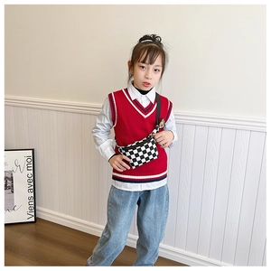 Detail von Kinder-Preppy-Outfit mit roter Strickweste und karierter Umhängetasche