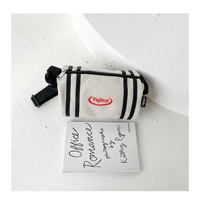 Detailed macro view of cream canvas bucket bag with black stripes and red embroidery