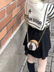 Detail of a mini round tricolor leather crossbody bag with a slim gold chain strap