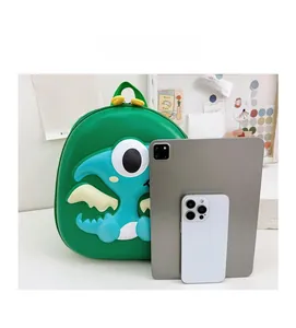Size comparison of green 3D dinosaur hardshell backpack with tablet and phone