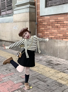 Detailed view of child's autumn outfit featuring a mini chain bag and knit sweater