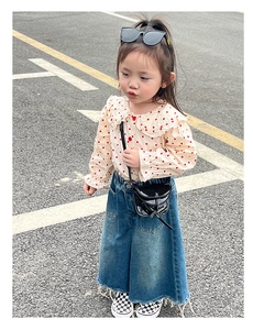 Detail view of mini black crossbody bag with tassel on a stylish girl outfit