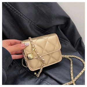 Detail of gold quilted mini bag with metallic chain strap and ball pendant decoration