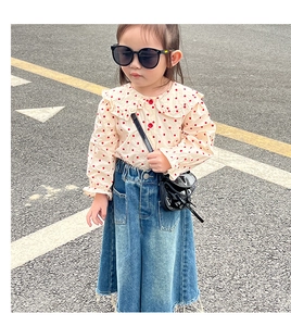 Close-up of a mini black patent leather crossbody bag with kids retro polka dot outfit