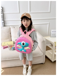 Pink hardshell toddler backpack with blue cartoon dragon shown in a home setting