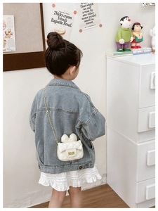 Detail of cream white quilted crossbody bag with bow and gold chain on child model