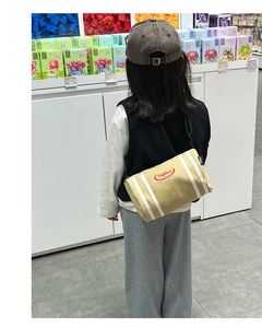 Close-up of kids canvas bucket bag featuring red embroidery and adjustable black strap