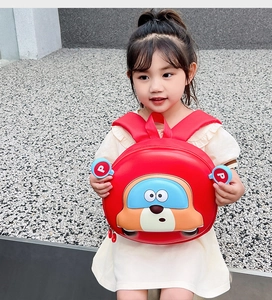 Toddler red hard-shell car backpack with blue ear accents worn by a little girl