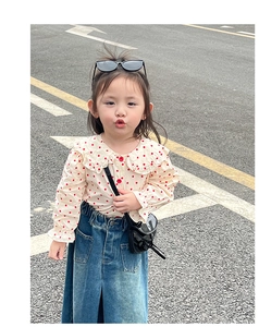 Detailed view of child fashion set featuring polka dot blouse and denim skirt with crossbody bag