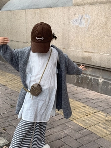 Detail of children's mini round brown bag with bronze chain on a grey knit cardigan
