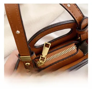 Close-up of golden hardware zipper and strap buckle on brown PU leather mini bag