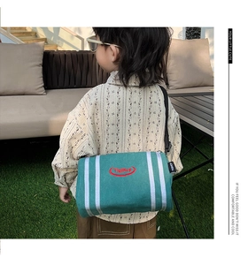 Detail of green canvas kids bucket bag with white vertical stripes and red oval logo