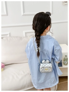 Detail of silver quilted leather kids cross body bag with bow and gold chain strap
